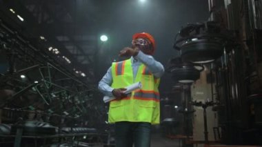 Modern güvenlik üniforması giyen siyah saç denetçisi lastik deposunda yürüyor..