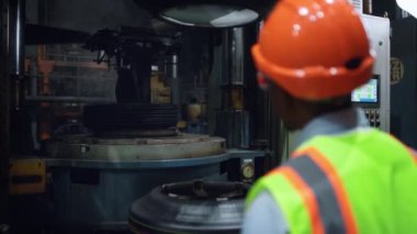 Lastik imalat fabrikasında metal işçiliği analiz eden bir işçi..