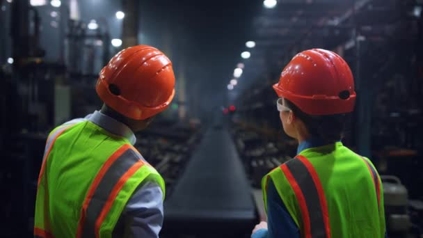 Fokuserade ingenjörer diskuterar arbete på en enorm däckfabrik för energitillverkning. — Stockvideo