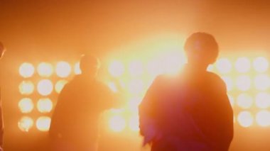 Dans eden erkek siluetleri, parlak spot ışıkları kulübünde hip hop yapıyorlar.. 