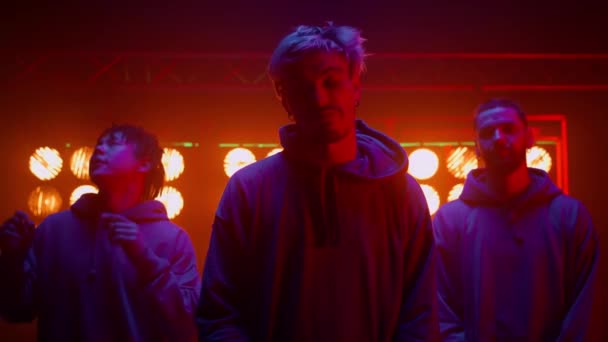 Hip-hopowy zespół mężczyzn stojących blisko klubu nocnego. Lider zespołu pokazuje kciuki w górę. — Wideo stockowe