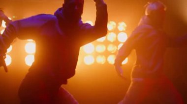 Sahne ışıkları altında hiphop yapan zıplayan dansçılar. Çevik erkekler takımı dans ediyor.