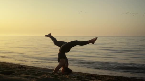 Sıska kız açık havada dengesini koruyor. Yogacı kadın sahilde çalışıyor. — Stok video