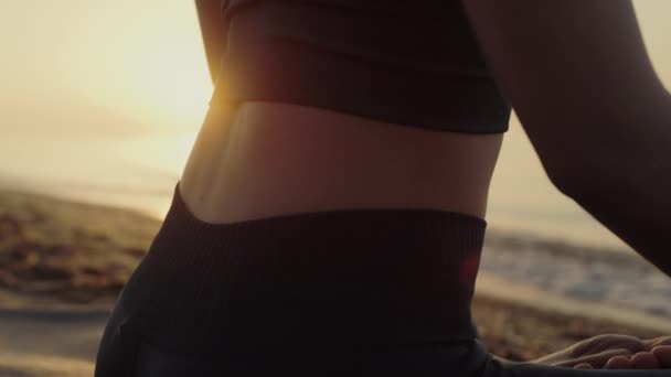 Sportieve vrouw zitten lotus positie oefenen yoga asana bij zonsondergang close-up. — Stockvideo