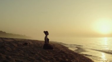 Yoga yapan kadın kumlu sahilde meditasyon yapıyor. Kadın doğada dinleniyor..