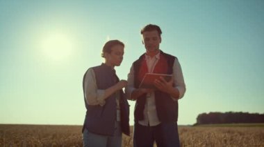 Agronomlar güneş ışığında tablet bilgisayarı tutuyorlar. Tarım endüstrisi çalışanları