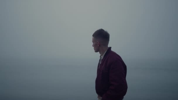 Sad guy walking ocean coast in foggy morning. Casual man looking sea view — Vídeos de Stock