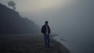 Sakin kulaklıklar sisli sahilde duruyor. Kulaklıkla müzik dinleyen adam.