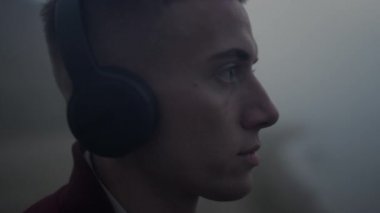 Ciddi adam kulaklıkları kameraya yakın görünüyor. Kulaklıkla müzik dinleyen adam.