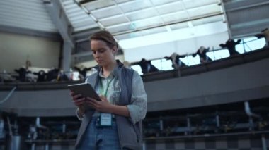 Odaklanmış işçi çiftliği süt sağma salonunu denetliyor. Modern üretim tesisi