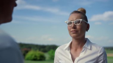 Kadınlar güneşli sahada golf hakkında konuşuyorlar. Sporcu dışarıda konuşuyor..