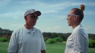 İki golf oyuncusu golf maçını golf sahasında tartışıyor. Güneşli bir günde mutlu çift sohbeti