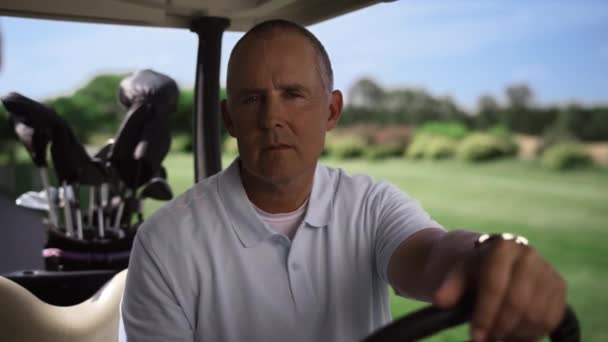 Självsäker golf professionell utseende kamera i klubbar väska vagn utanför. Idrottsbegreppet — Stockvideo