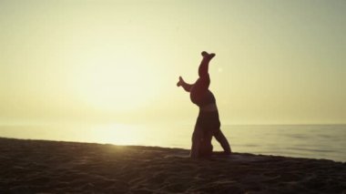 Yogacı kadın gün batımında baş aşağı duruyor. Baş aşağı duran güçlü kız.