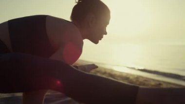 Kumsalda jimnastik yapan sporcu kadın. Yoga yapan kadın vinç duruşu yapıyor.