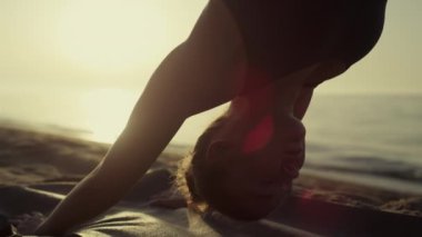 Yoga woman standing downward facing dog practicing svanasana at sunset close up.