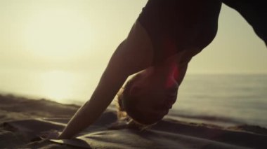 Yogi kızı asana egzersizi yapıyor. Kumlu sahilde yüz üstü poz veriyor. Yaklaş.. 