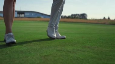 Golf çift bacakları çimlerde yürüyor. İki zengin insan golf kulübünde geziniyor.