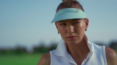 Golf oyuncusu yeşil sahada golf kulübünün tadını çıkarıyor. Güneş ışığına bakan kadın golfçü.