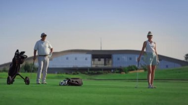 Lüks golfçüler dışarıda oynamaktan hoşlanırlar. Spor grubu yeşil yolda duruyor.