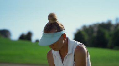 Confident woman playing golf on fairway. Golfer swinging ball at country club.