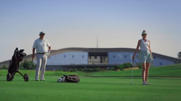 豪華なゴルファーは屋外フェアウェイで遊ぶことを楽しむ。緑のコースにスポーツグループスタンド — ストック動画
