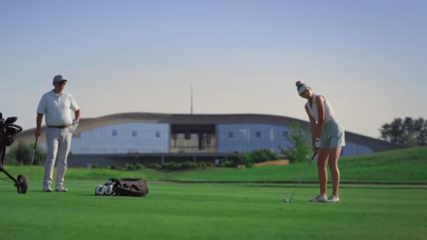 Jugadores del equipo de golf golpeando pelota en el club de campo de golf. Pareja disfrutar de la actividad. — Vídeo de stock