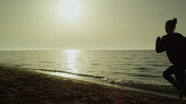 Visszapillantó futó nő a nyári naplementében. Lány fut tengerparton a sportruházat. — Stock videók