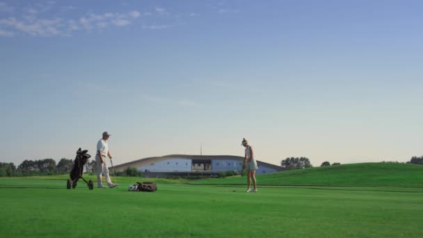 Professional golf people play game on fairway. Couple practice on sunset course. — Stockvideo