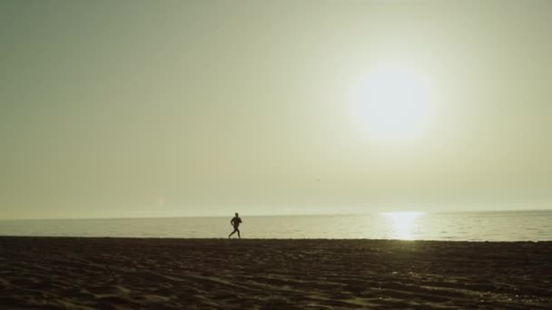 Ismeretlen, tengerparti sportoló. Silhouette kocogó nő naplementekor. — Stock videók