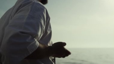 Bilinmeyen karateci elleri gün batımında savaş egzersizleri yapıyor. Dışarıda kimonoyla dövüş sanatları pratiği yapan sporcu. Sahilde kas sporcusu eğitimi, güzel manzaranın tadını çıkarıyor. Spor hayatı..