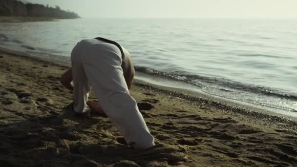 Gespierde Man Die Het Lichaam Uitrekt Het Zandstrand Avonds Karate — Stockvideo