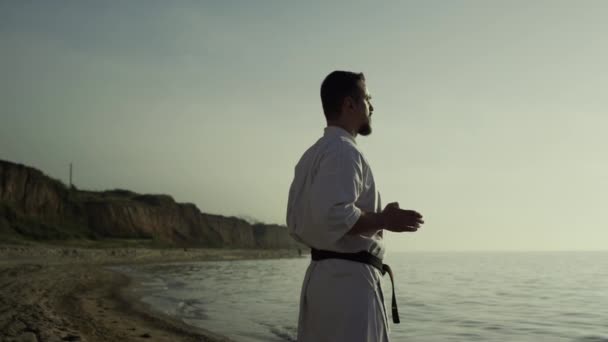 Brutalny Sportowiec Wykonujący Ćwiczenia Medytacyjne Piaszczystej Plaży Letni Wieczór Karate — Wideo stockowe