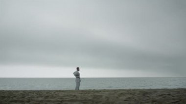 Kumsalda dövüş sanatları pratiği yapan aktif bir sporcu. Adam dışarıda karate eğitimi alıyor..