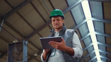 Agribusiness worker using tablet computer in shed. Dairy production engineer