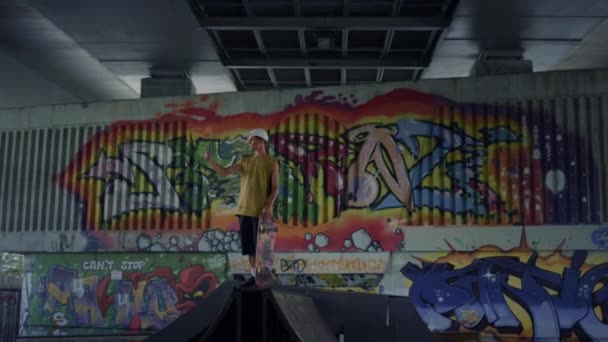 Grafiti duvarının arka planında cep telefonuyla selfie çeken bir genç.. — Stok video