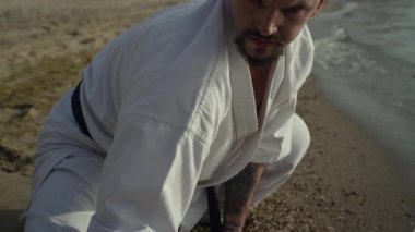 Kumsalda esneme antrenmanı yapan sportif bir adam. Etkin atlet antrenman dengesi