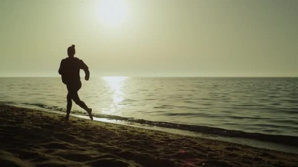 Fast woman running alone sand beach at sunset. Silhouette girl jogging near sea — Stockvideo