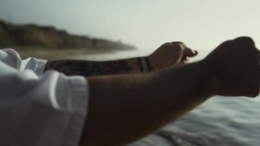 Tattooed man hands doing warm-up at sunset close up. Workout on summer nature.