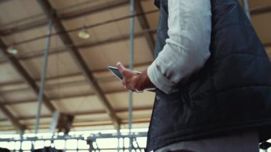 Dairy manager working cowshed alone. Worker hands holding pad computer closeup