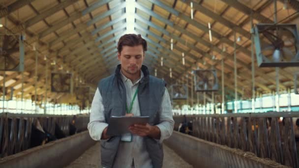 Livestock owner checking animal feedlots making notes on clipboard at cowshed. — Wideo stockowe