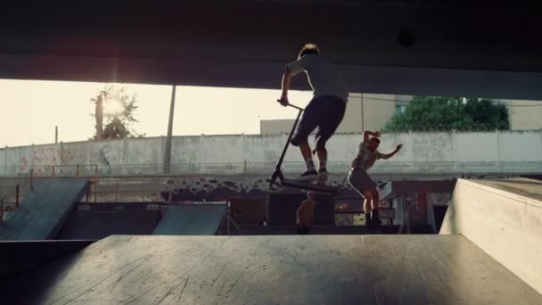 Teenage athletes performing stunt together at city bright sun skate park. — Stock video