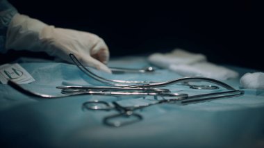 Koyu steril ameliyat odası yan görüntüsünde cerrahi aletlerle dolu bir masa.