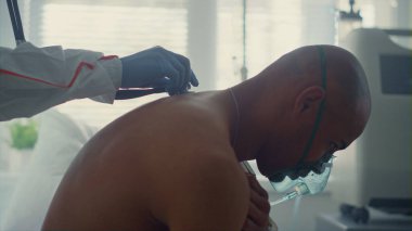 Hastane koğuşunda 19 numaralı hasta oksijen maskesi. Bilinmeyen hekim hasta adamı muayene ediyor.