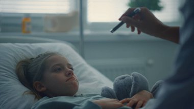 Doktor hasta koğuşunu ziyaret ediyor. Küçük üzgün hasta hastane yatağında yatıyor..