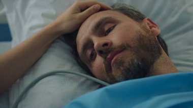 Hasta hasta, cerrahi tedaviden sonra yatakta yatıyor. Dişi el dokunuşu yüz yakın plan