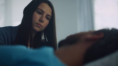 Cerrahi tedaviden sonra hasta yatağında yatıyor. Endişeli ziyaretçi, adamın üstüne otur.