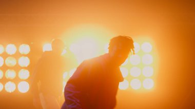 Dans eden erkek siluetleri, parlak spot ışıkları kulübünde hip hop yapıyorlar.. 