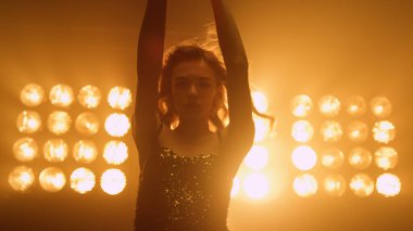 Stüdyo ışıklarında baştan çıkarıcı dans eden zarif bir kadın. Seksi kız hareket ediyor.