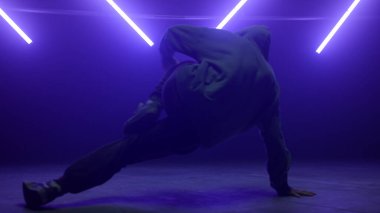 Neon ışıkla hip-hop yapan bilinmeyen bir adam. B-boy dans ediyor yerde.